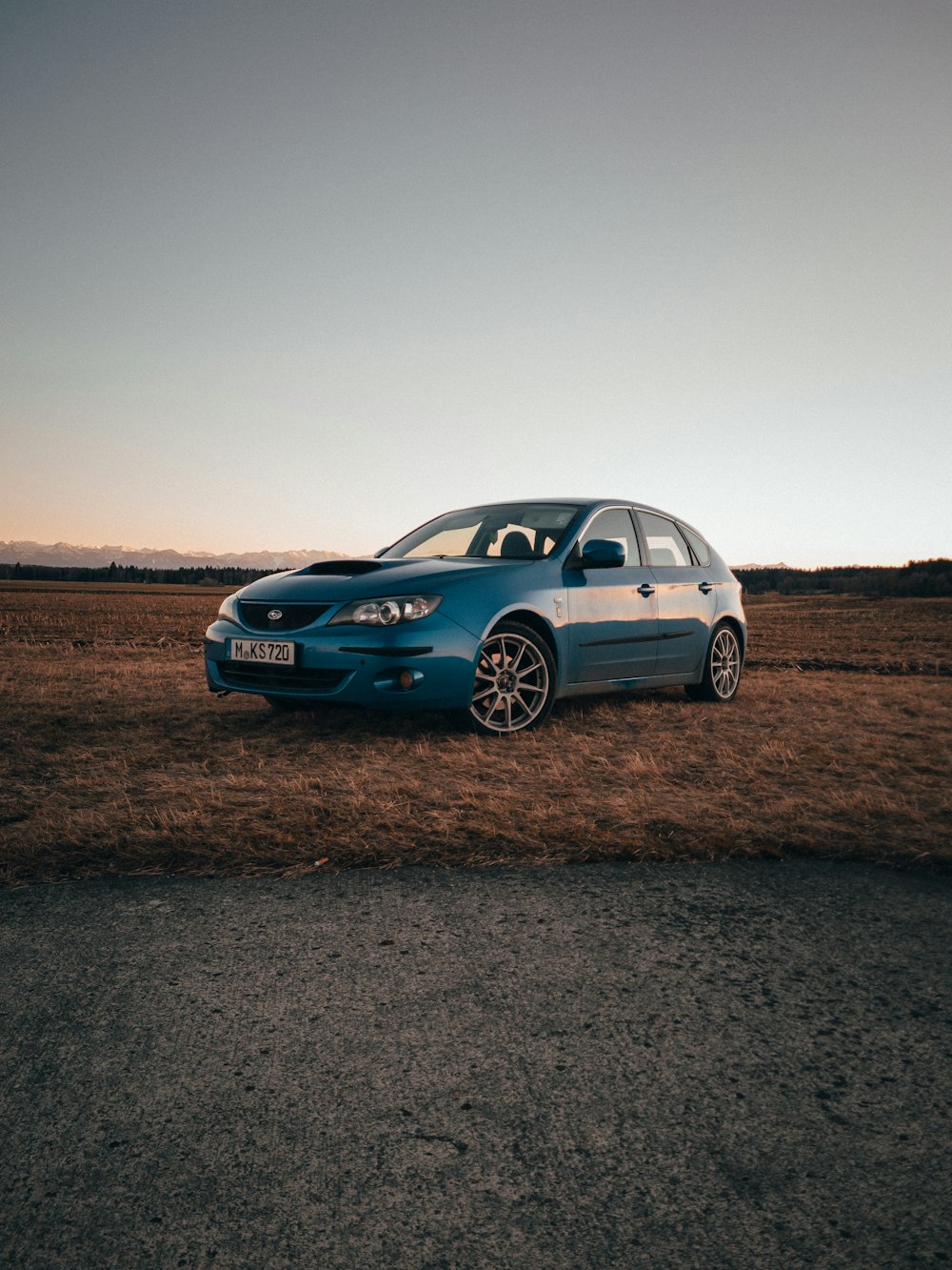 a blue car is parked in a field