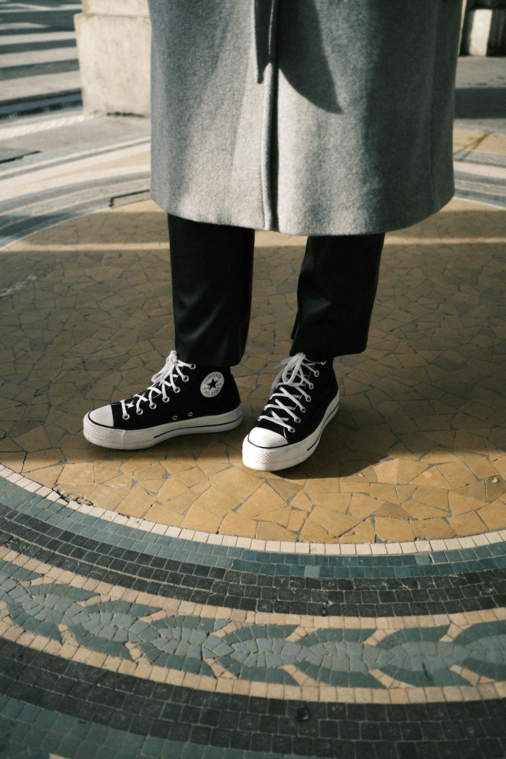 a person in black and white sneakers standing on a sidewalk photo – Free  París Image on Unsplash