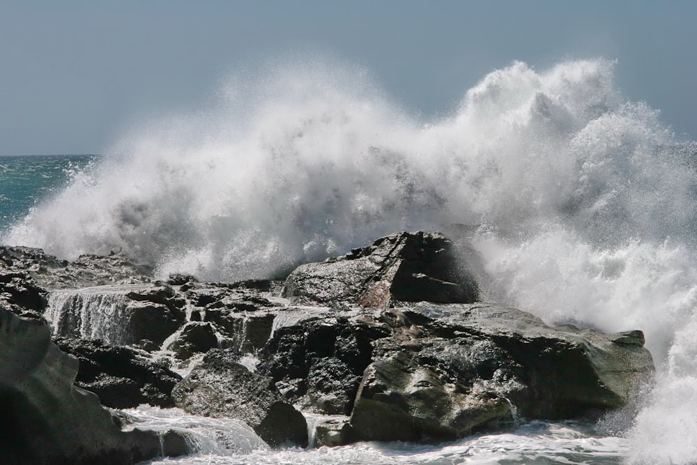 a large wave crashing over a rocky shore