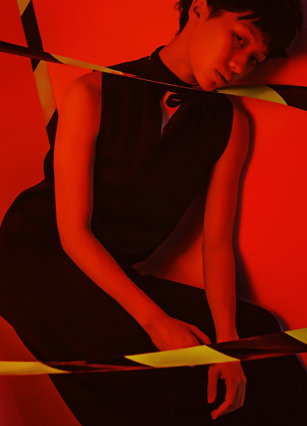 a woman in a black dress sitting on a red wall