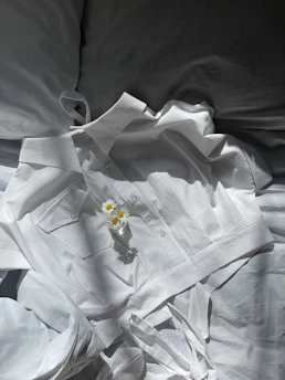A soft cotton tee and tailored pants laid out with fresh flowers nearby