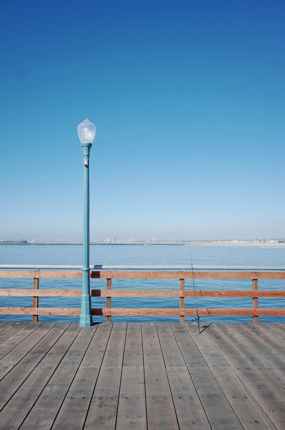 a light pole on a wooden pier next to the ocean