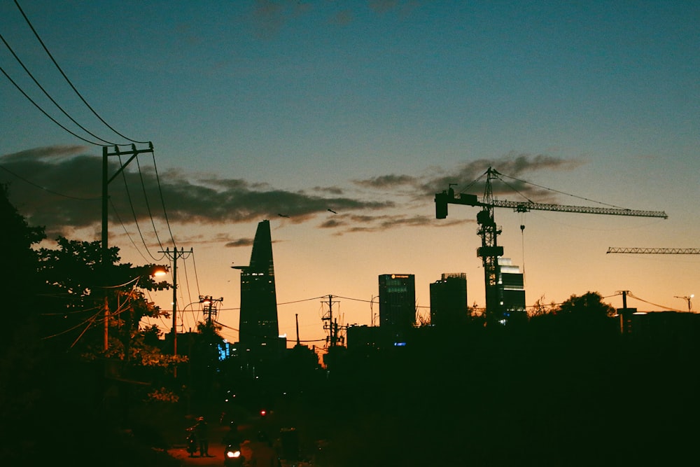 a city skyline at dusk with a crane in the distance