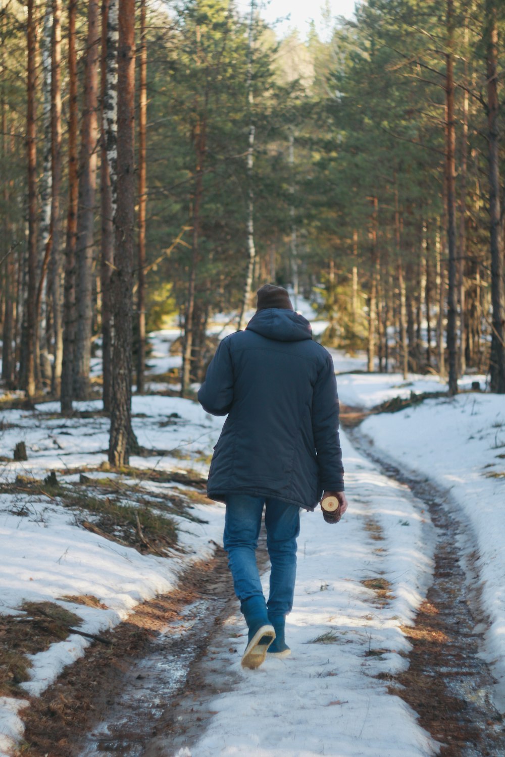 a man walking down a snow covered path in the woods