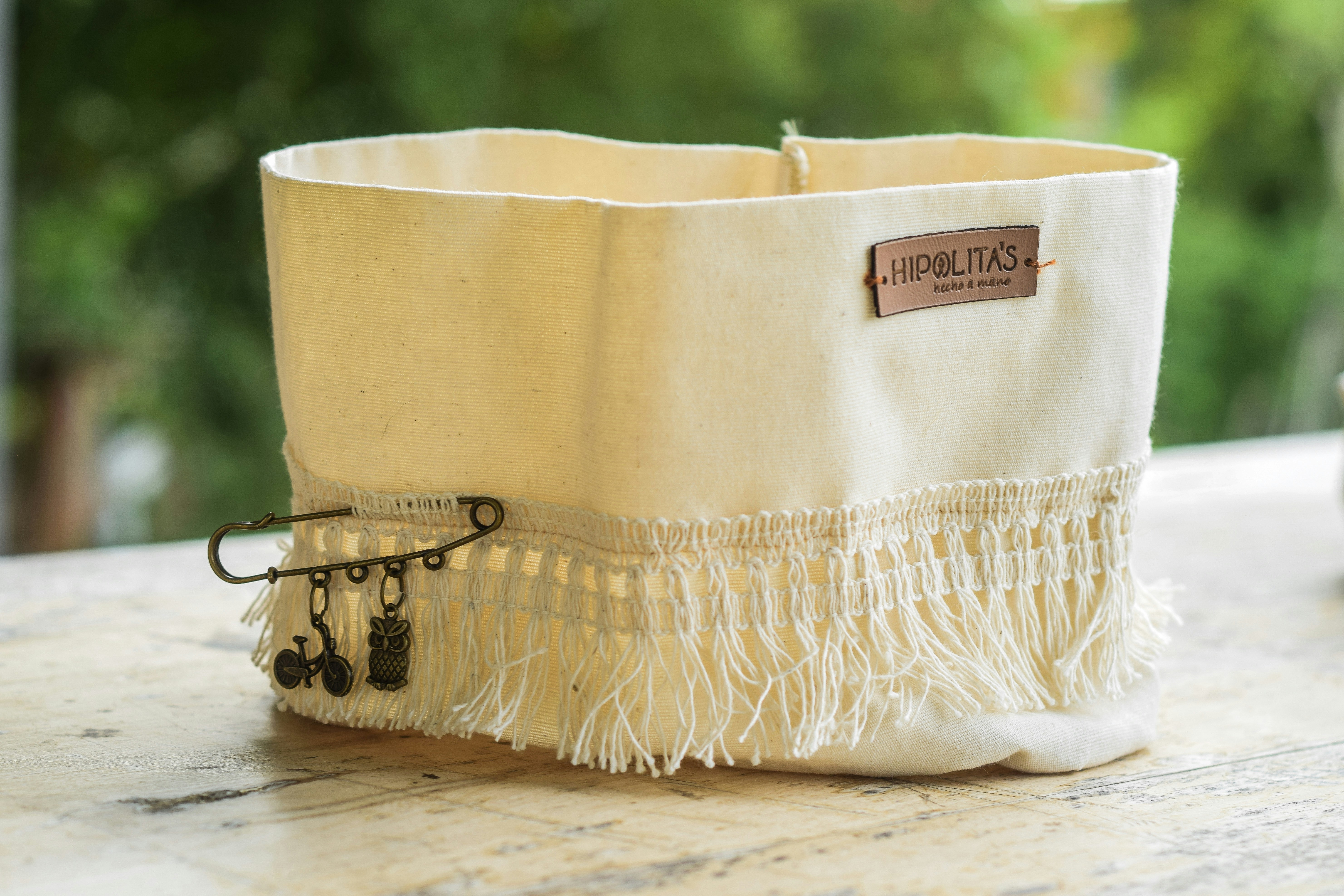 a white basket with a tassel on top of it