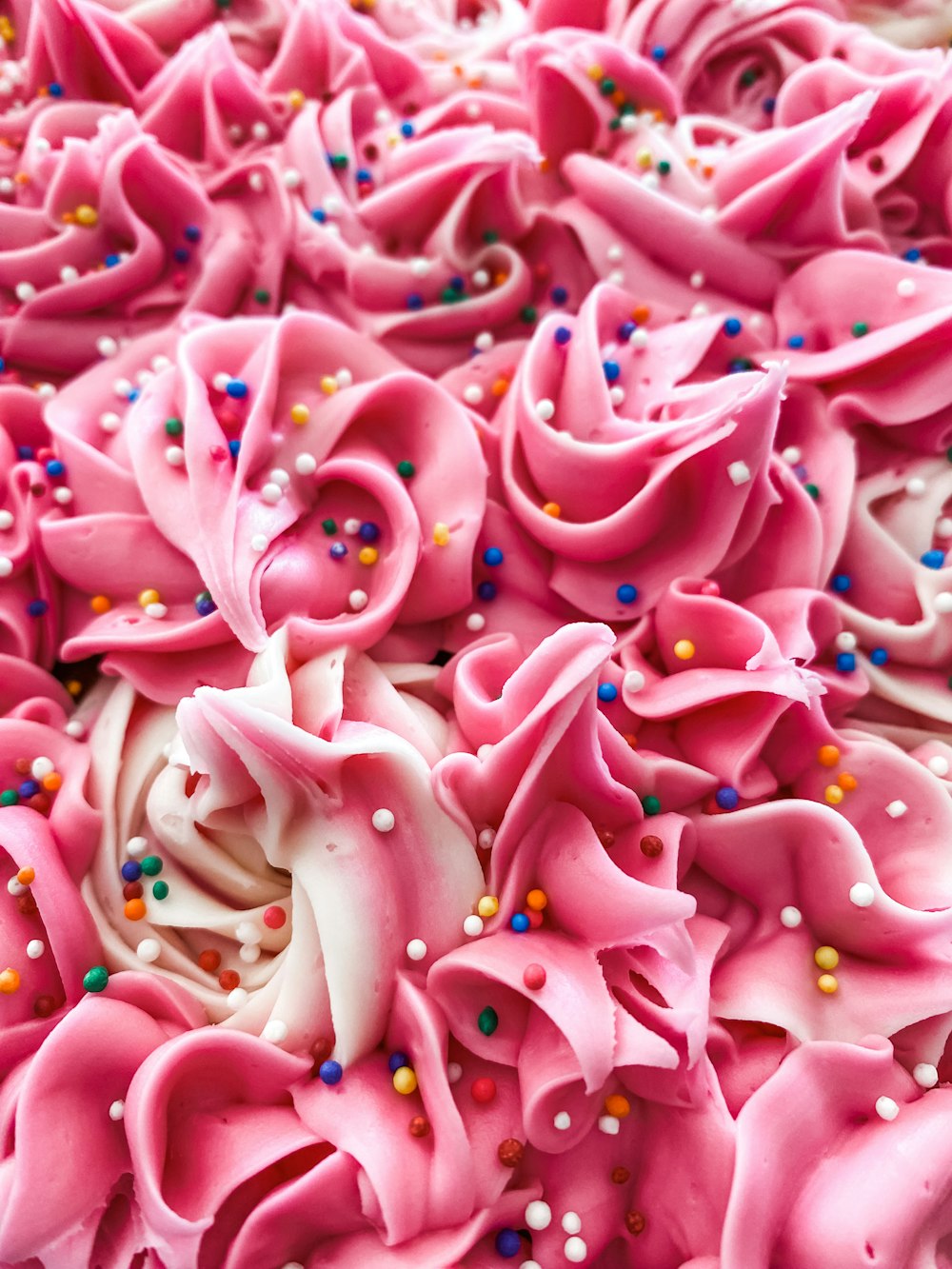 a close up of a pink cake with sprinkles