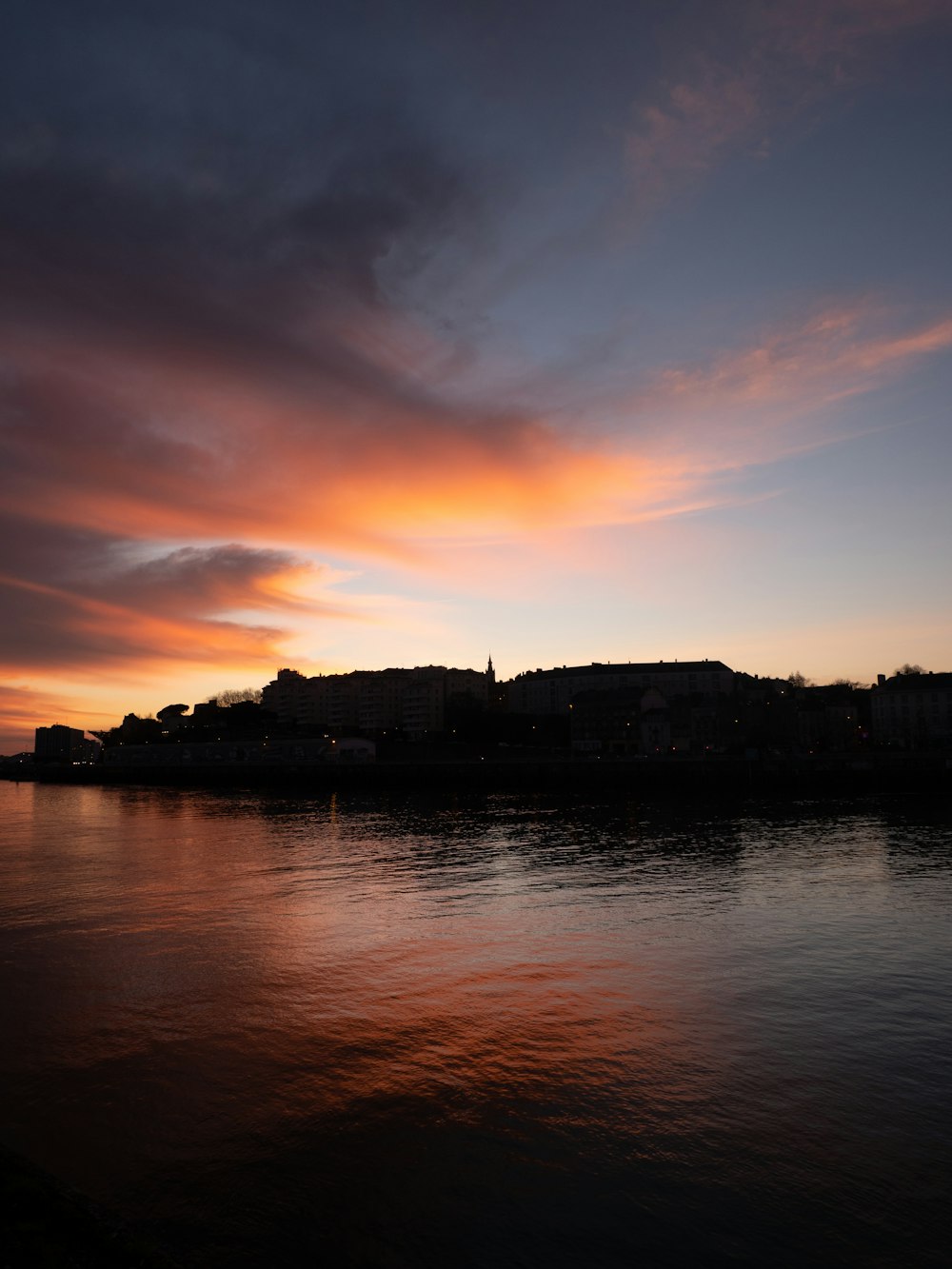 a sunset over a body of water with buildings in the background