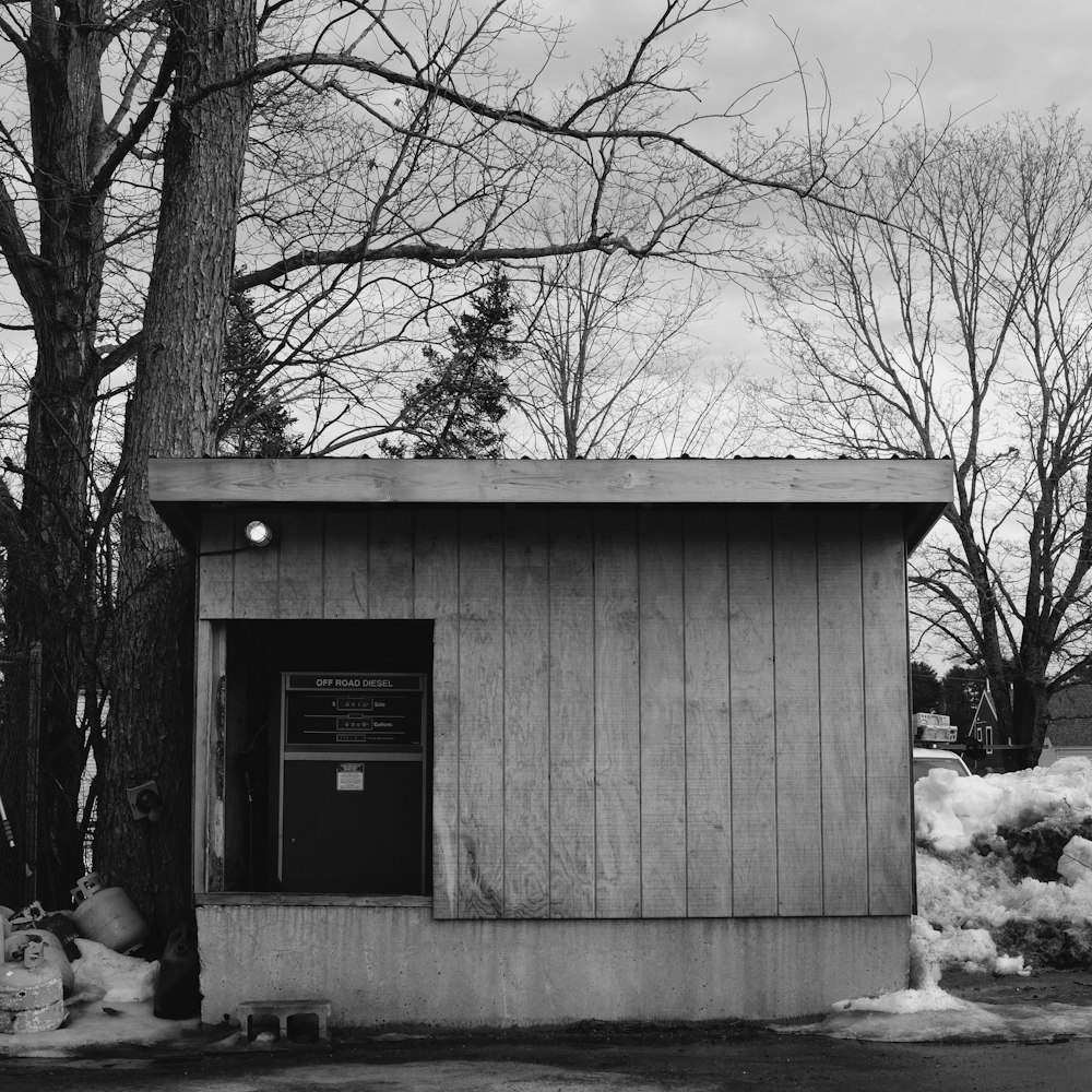 a black and white photo of a small outhouse