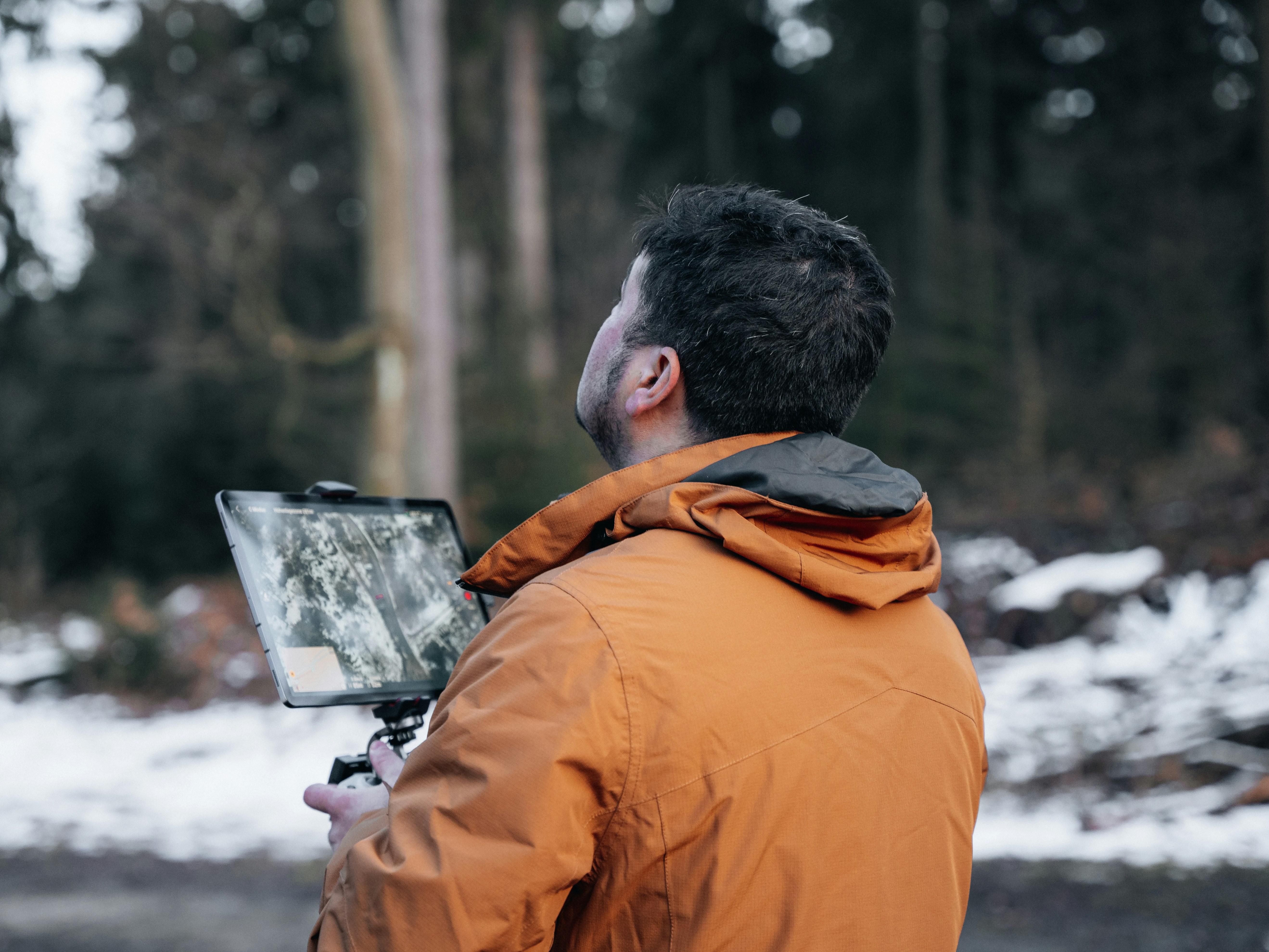 A man in an orange jacket holding a camera