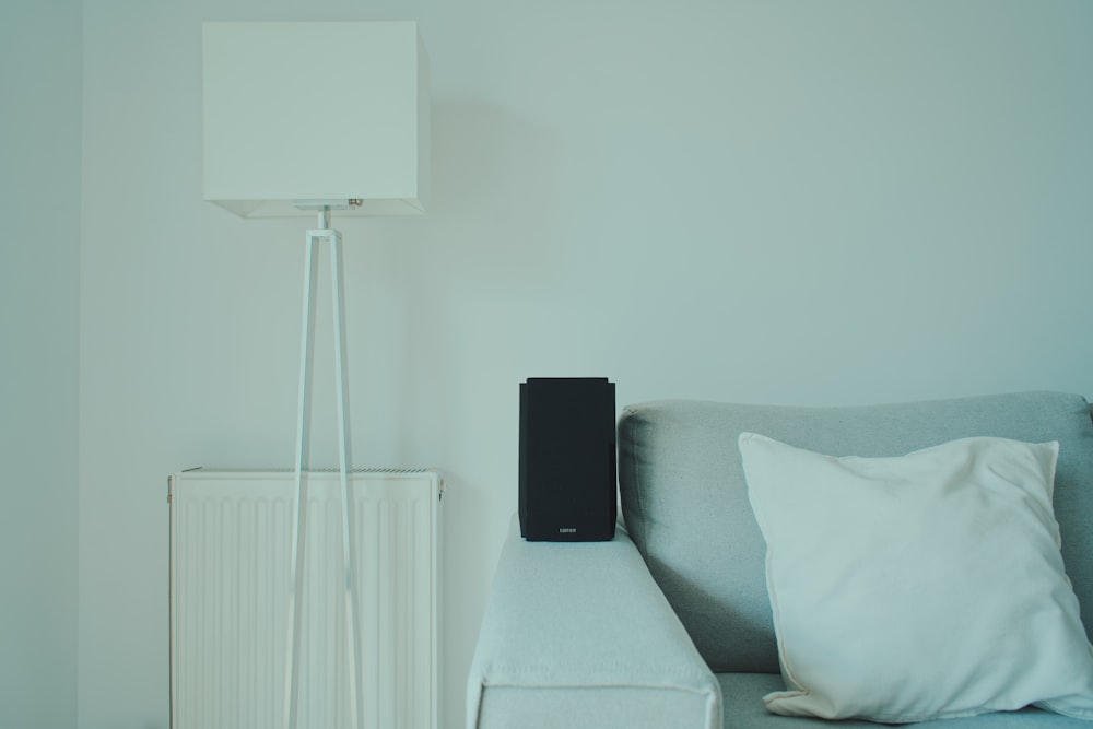 a couch with a pillow and a speaker on top of it