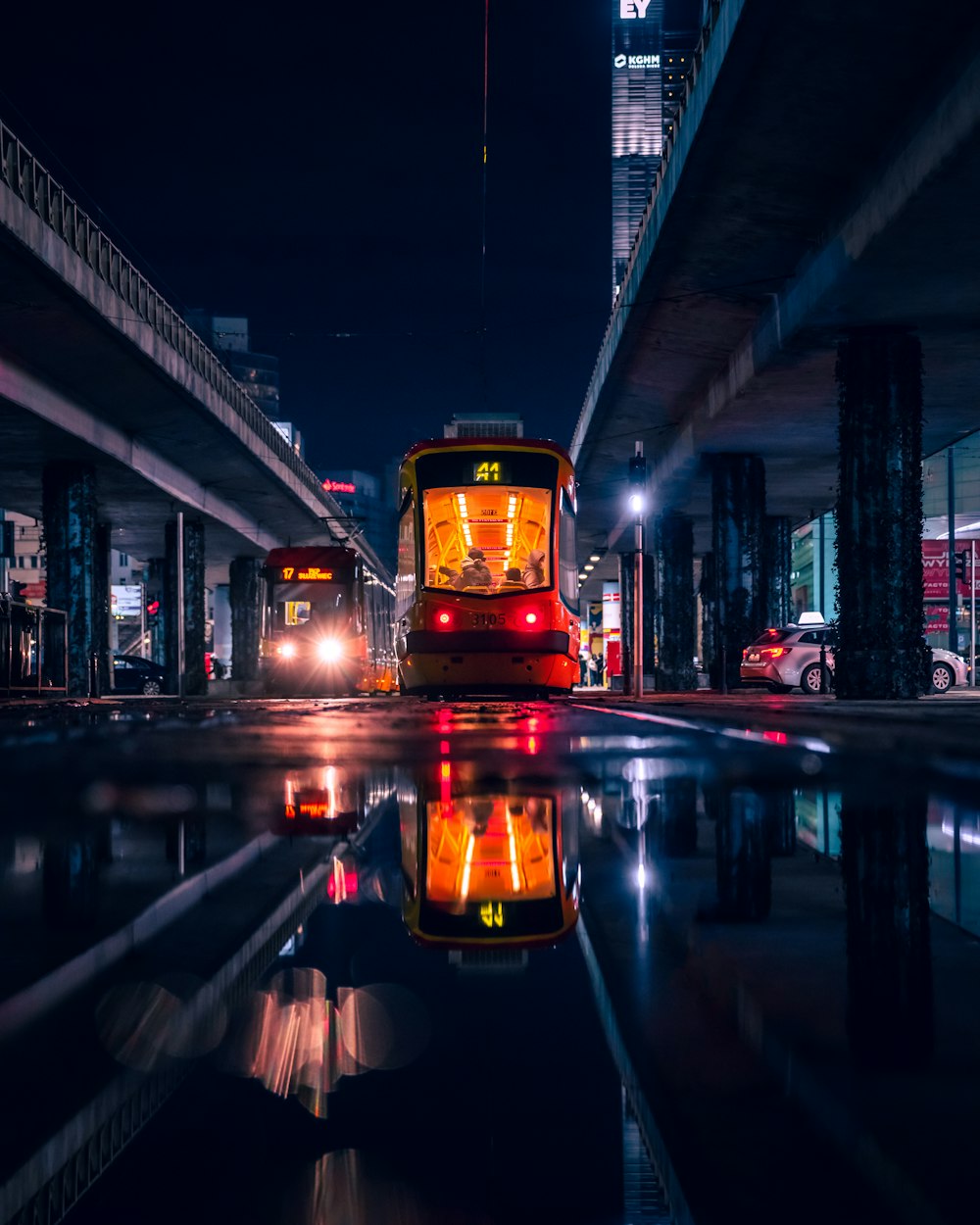 a red bus driving down a street next to a tall building