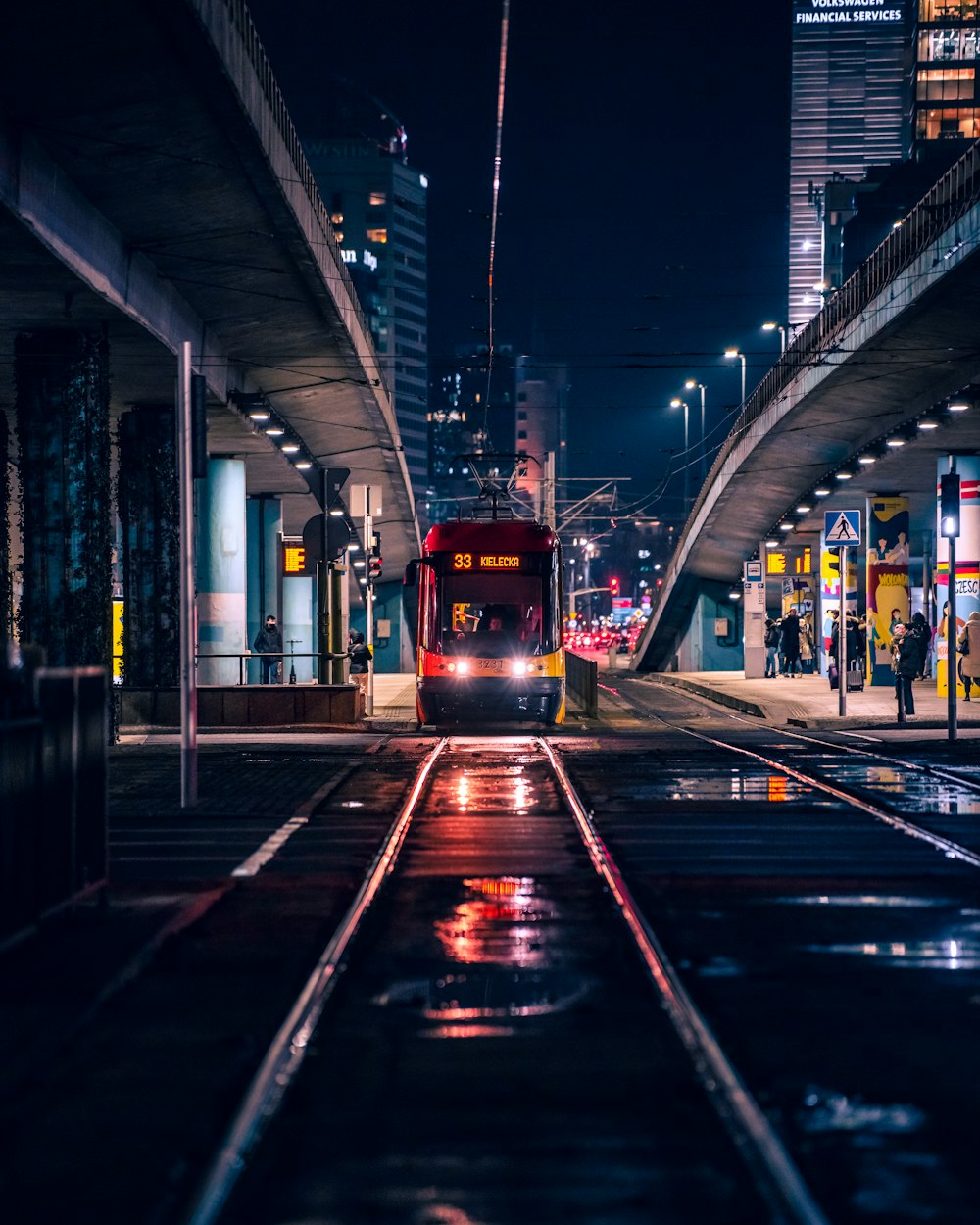 a red train traveling down train tracks next to a tall building