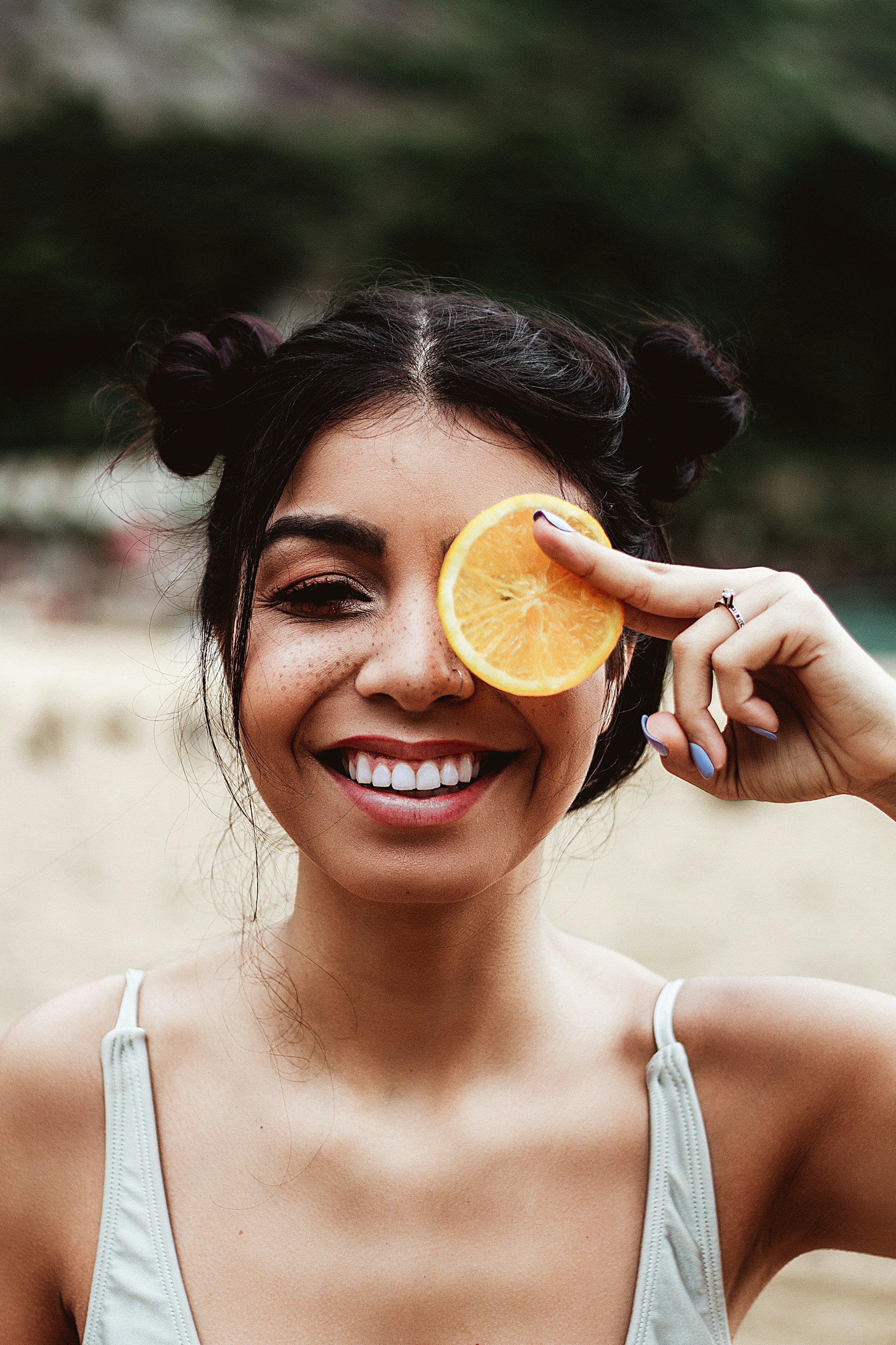 a woman holding an orange slice up to her eye