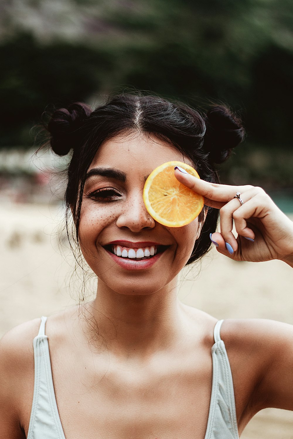 a woman holding an orange slice up to her eye