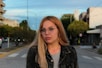 a woman with glasses standing on the side of the road