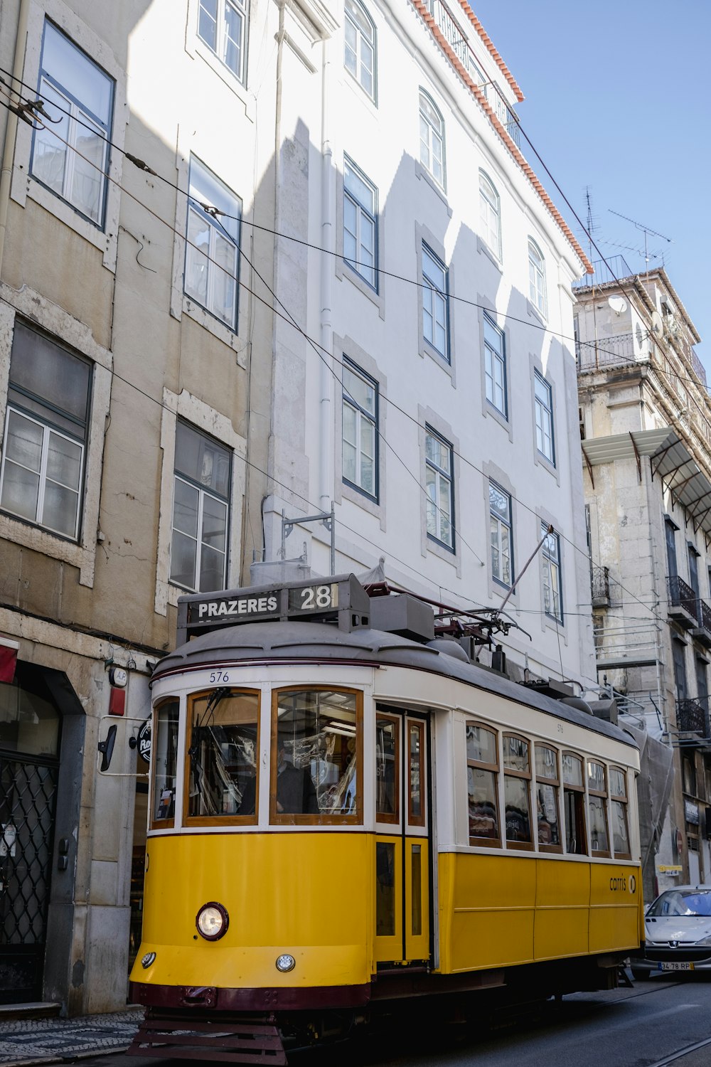 a yellow trolley car traveling down a street next to tall buildings