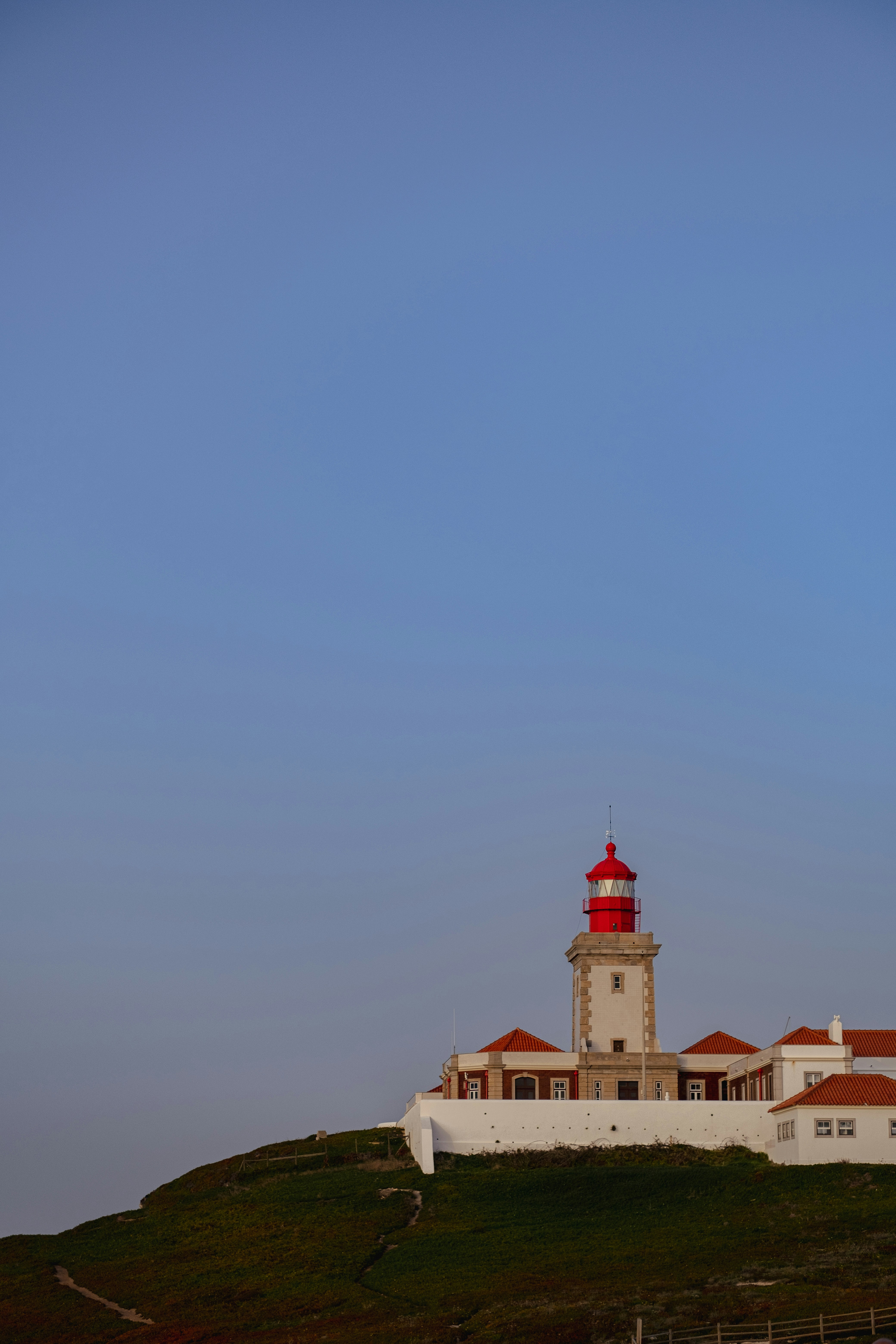 a lighthouse on top of a hill with a blue sky in the background