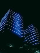 Futuristic modern office building with blue neon accents at dusk.