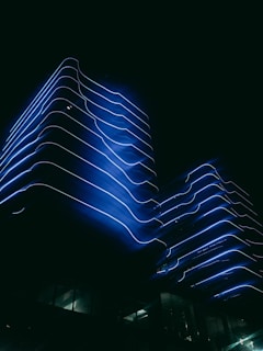 A sleek, modern office building with electric-blue neon accents glowing softly at dusk.