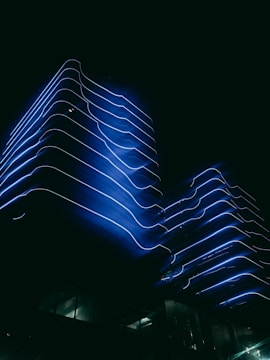 Futuristic modern office building with blue neon accents at dusk.