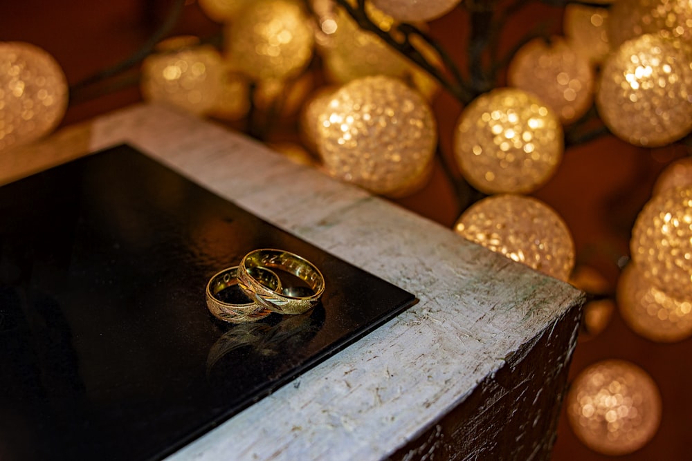 two gold wedding rings sitting on top of a table