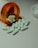 Several white capsules with numbers are scattered across a surface, with an orange prescription bottle lying on its side. The pills spill out of the container, and a white bottle cap is visible nearby.
