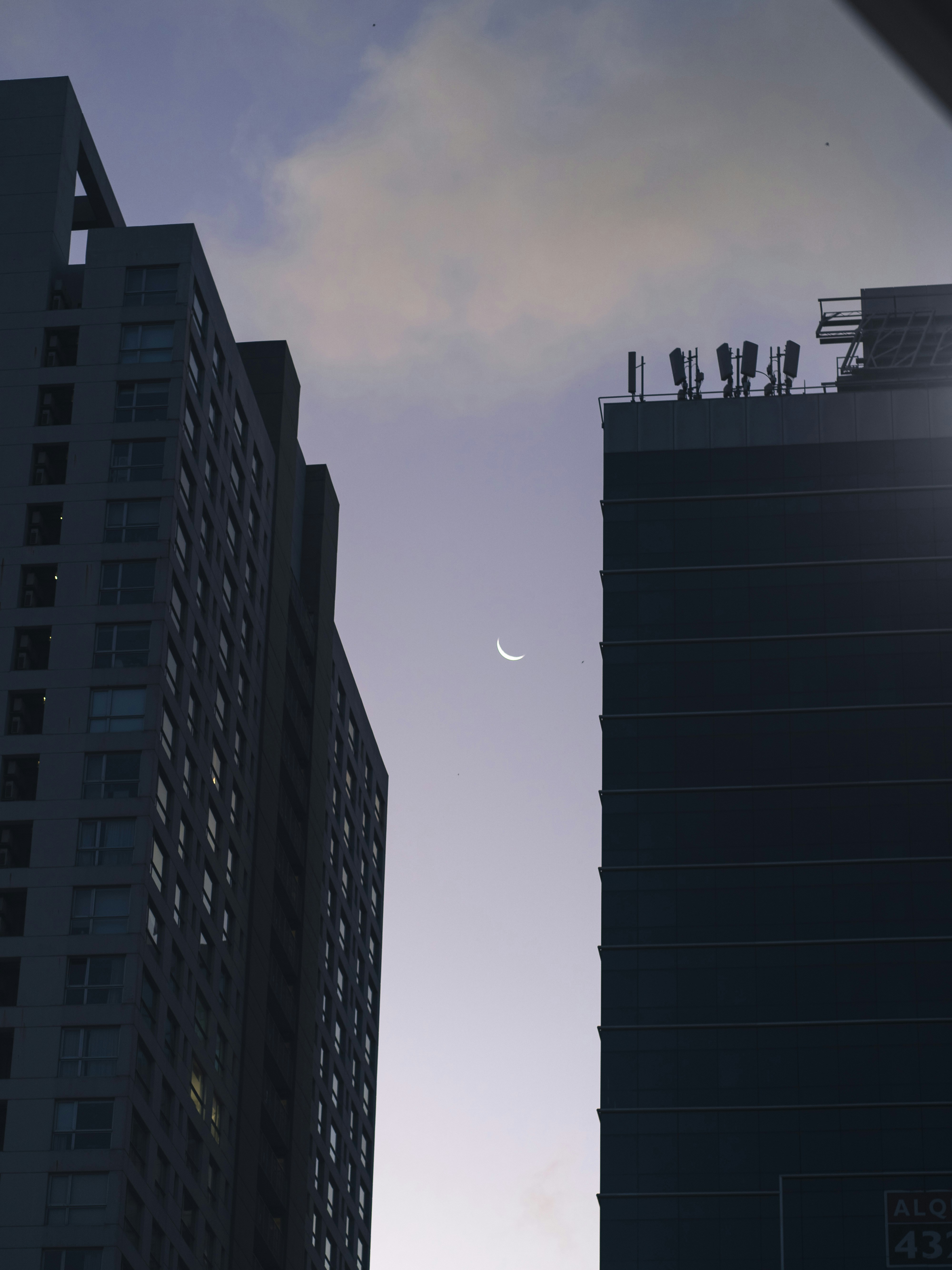 two tall buildings with a half moon in the sky
