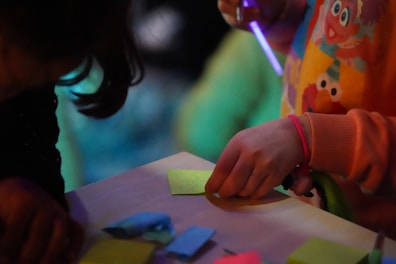 A child coloring inside a pocketful press creative activity book with crayons scattered around.