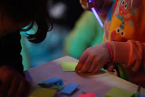 Close-up of child drawing while being gently observed during an evaluation session.