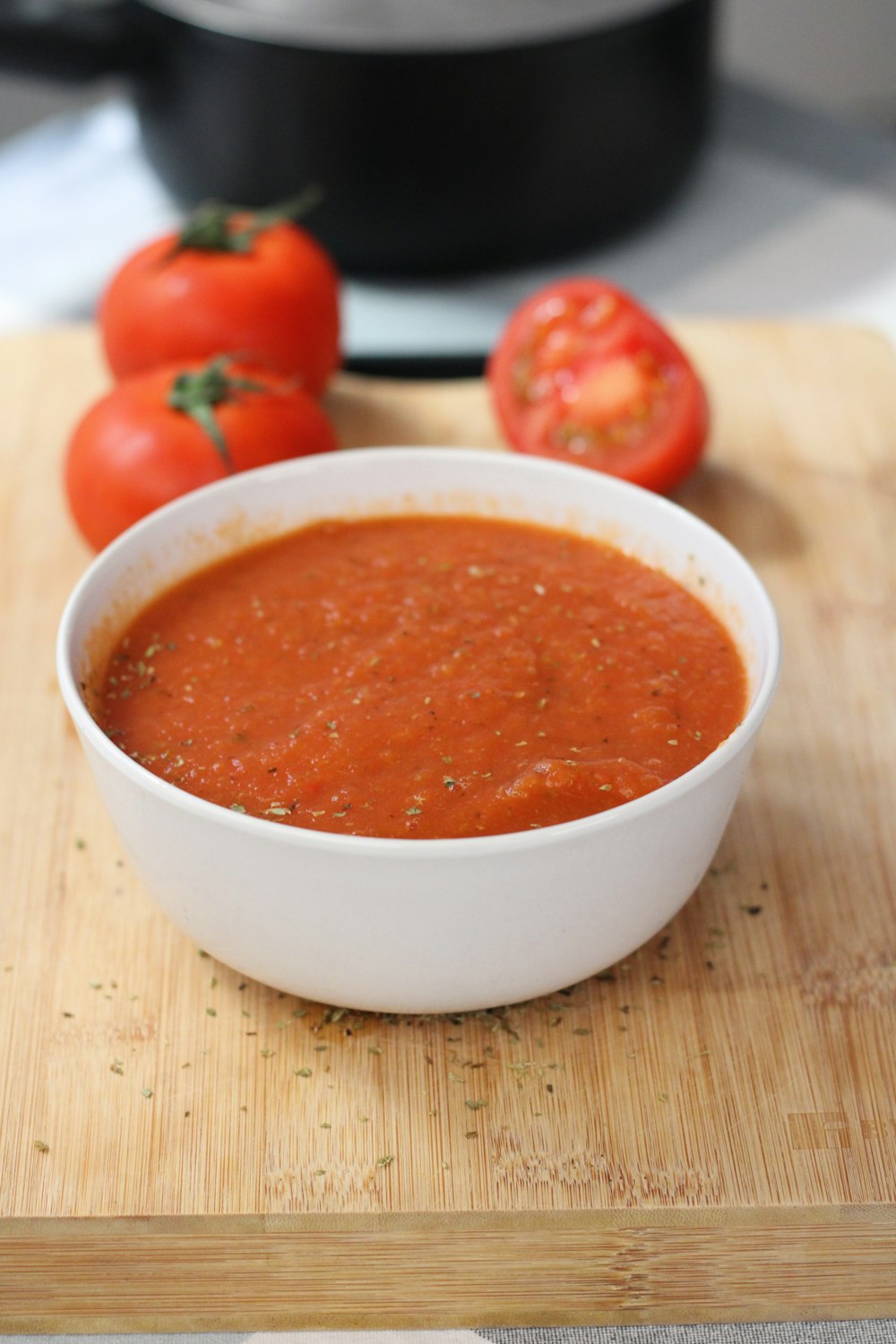 a bowl of tomato soup on a cutting board