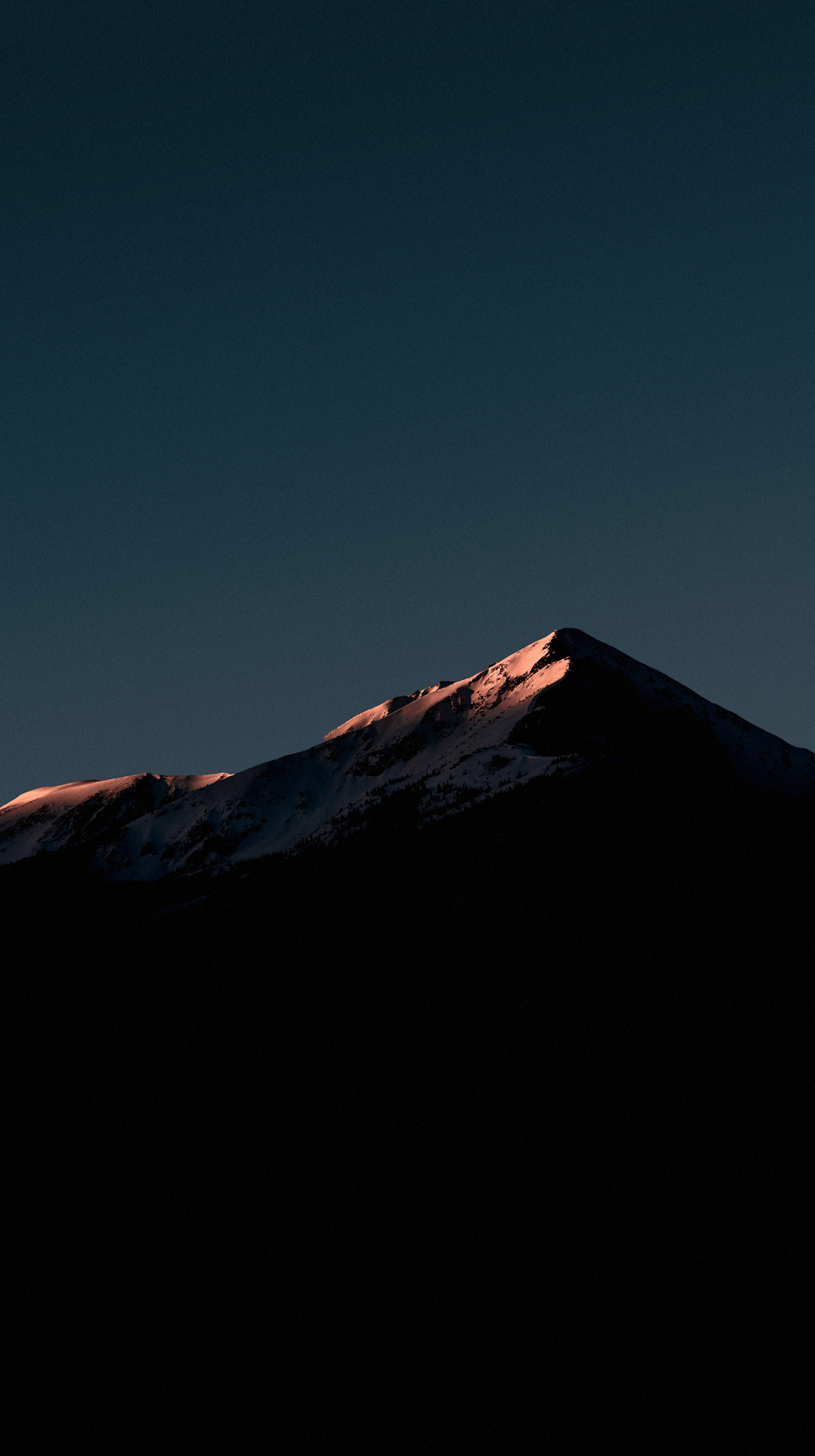 a very tall mountain covered in snow under a blue sky