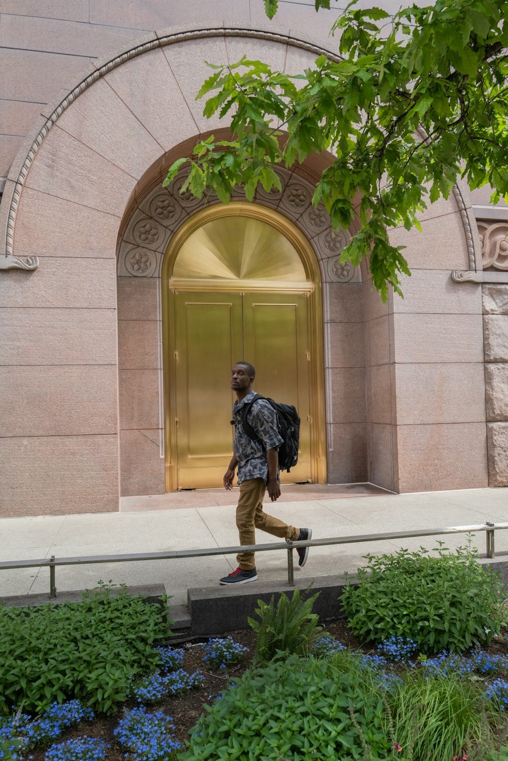 Un homme avec un sac à dos passant devant un bâtiment