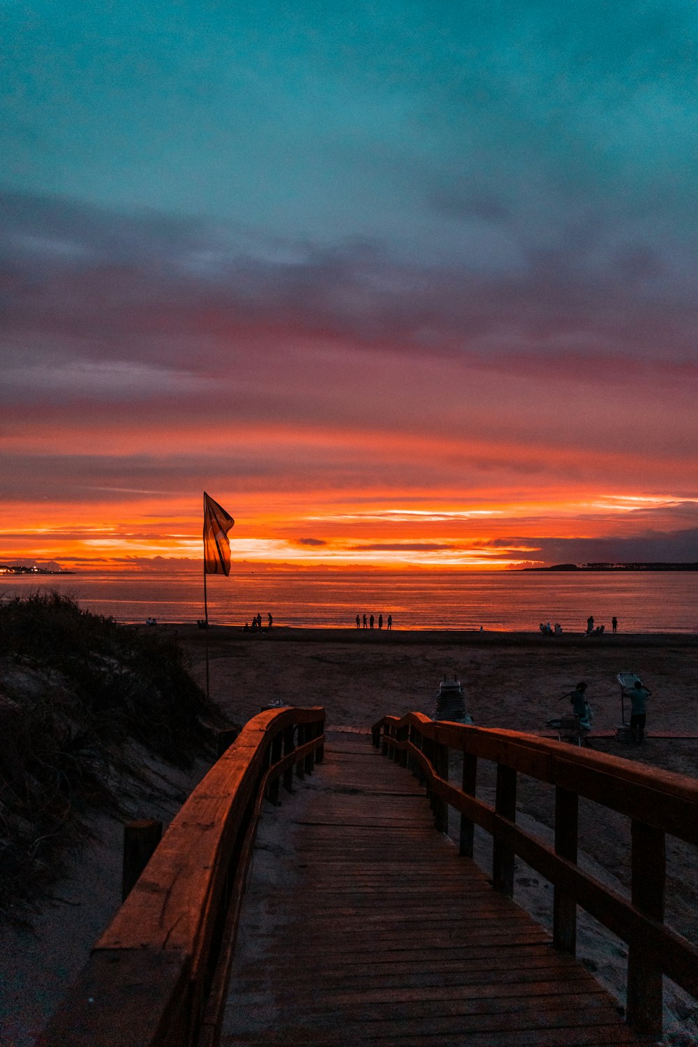 a wooden walkway leading to the beach at sunset