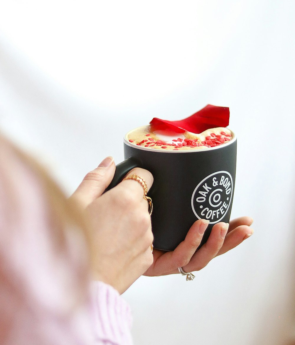 a woman holding a cup of coffee with a red bow on top