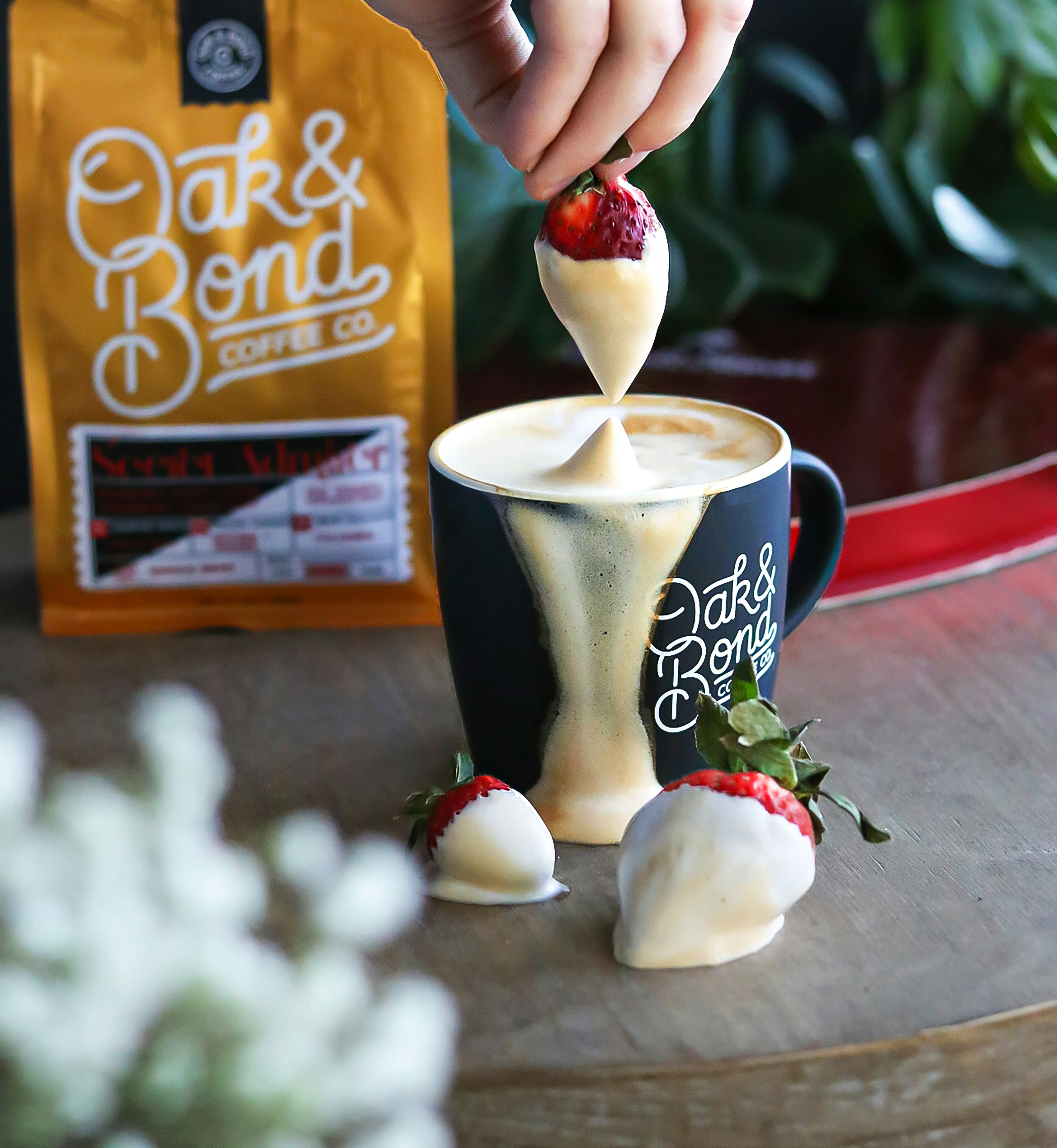 a person dipping a strawberry into a cup of coffee