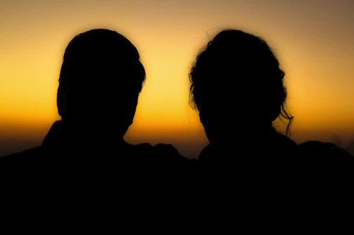 A high-contrast black and mineral-colored portrait of a couple at sunset.