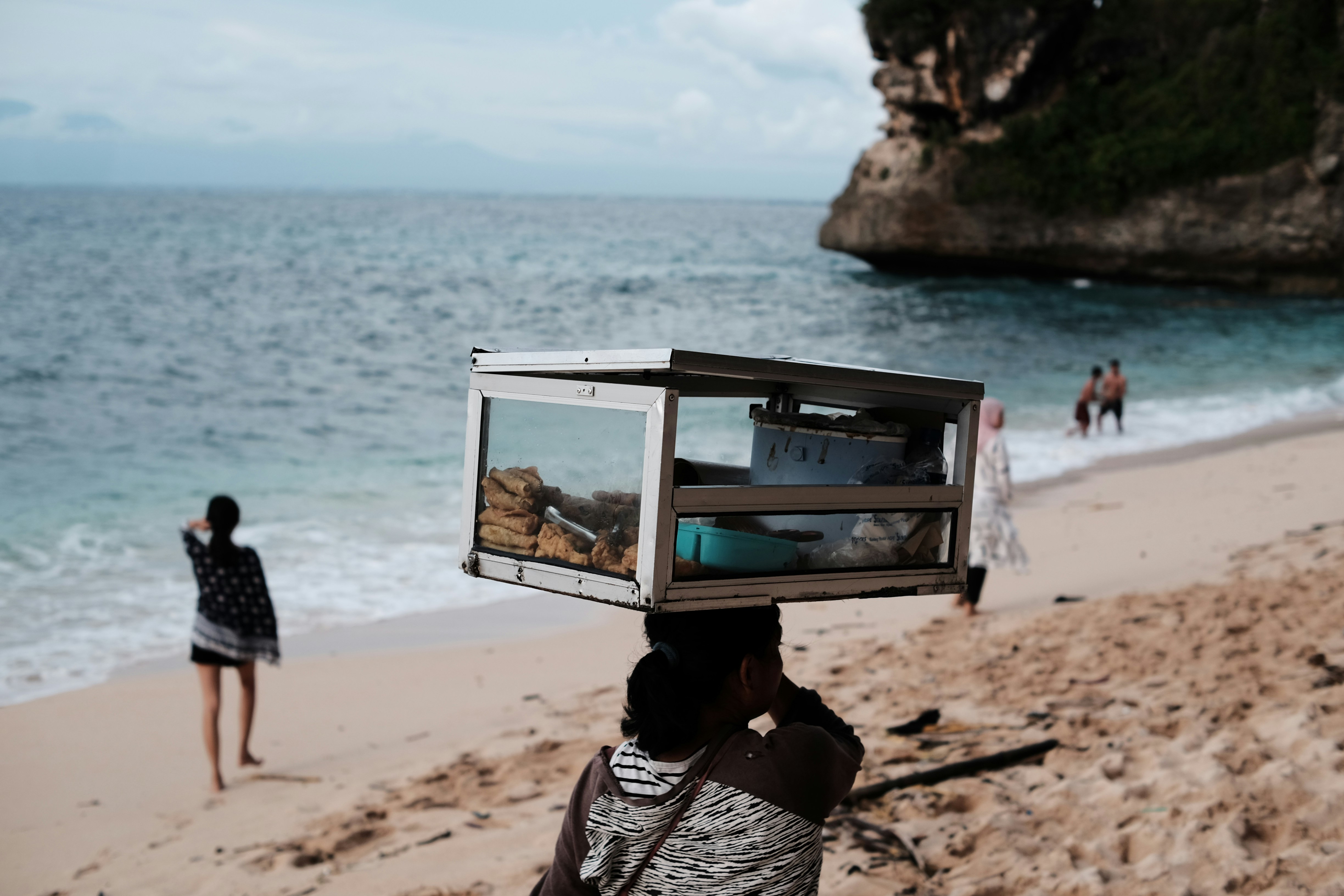 a person on a beach with a microwave on their head