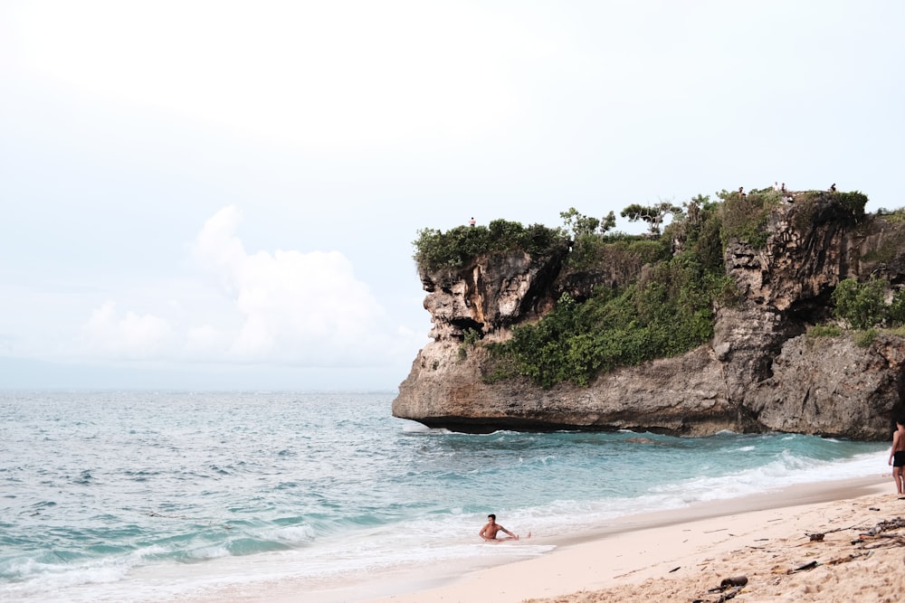 a couple of people standing on top of a sandy beach