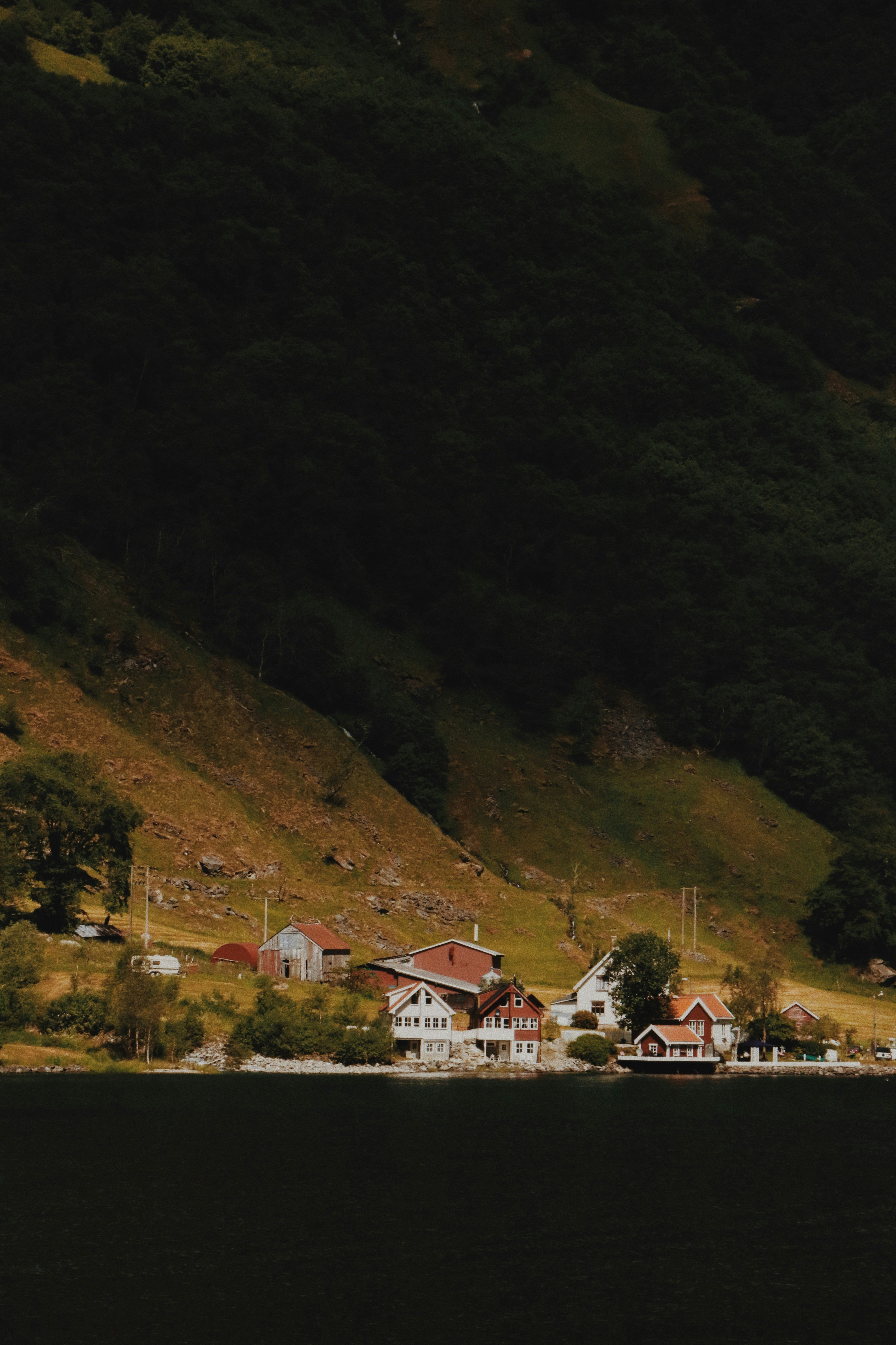 a boat floating on top of a lake next to a lush green hillside