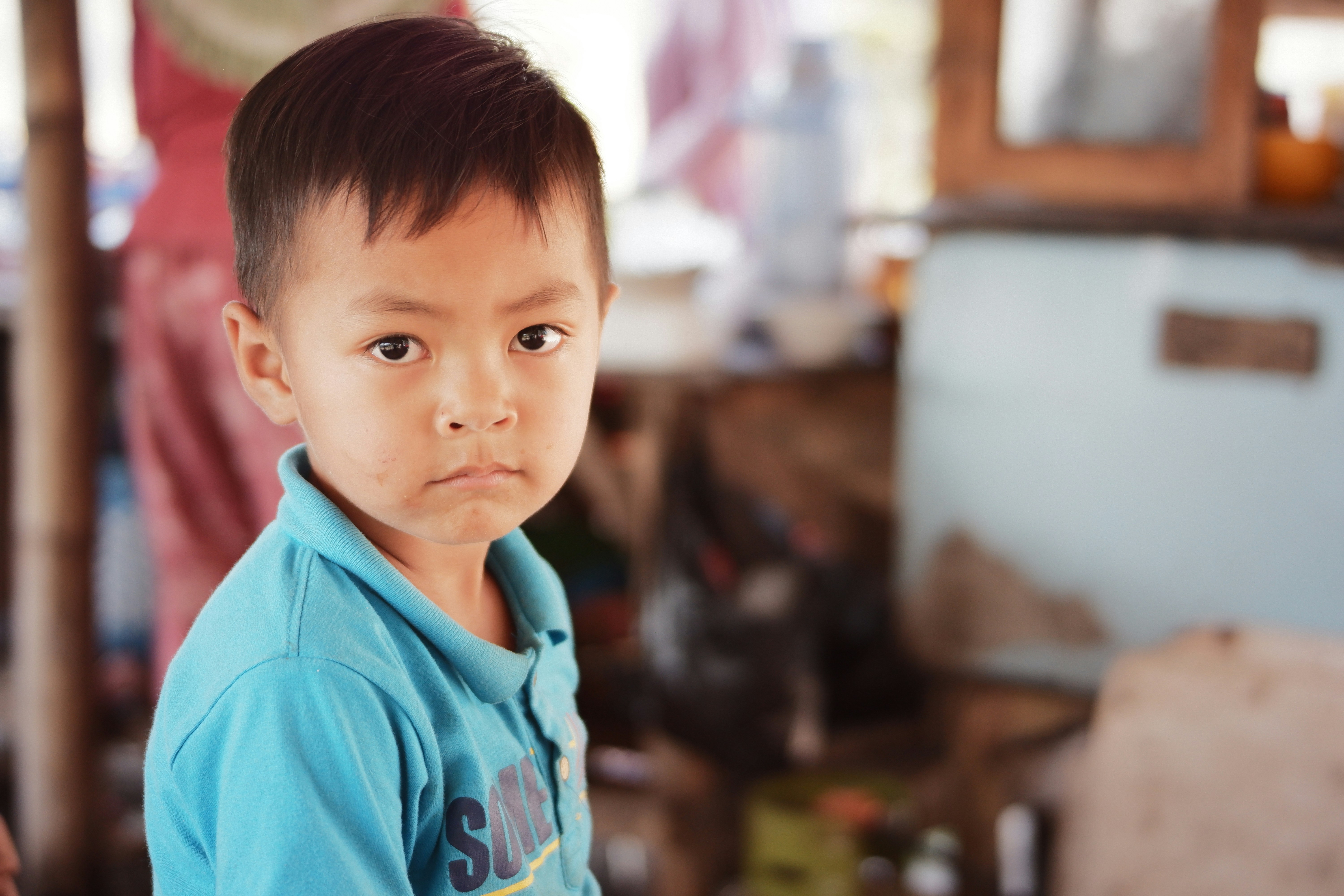 a young boy in a blue shirt looking at the camera
