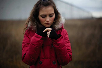 a woman in a red coat looking at her cell phone