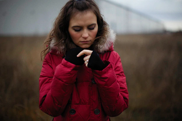 a woman in a red coat looking at her cell phone