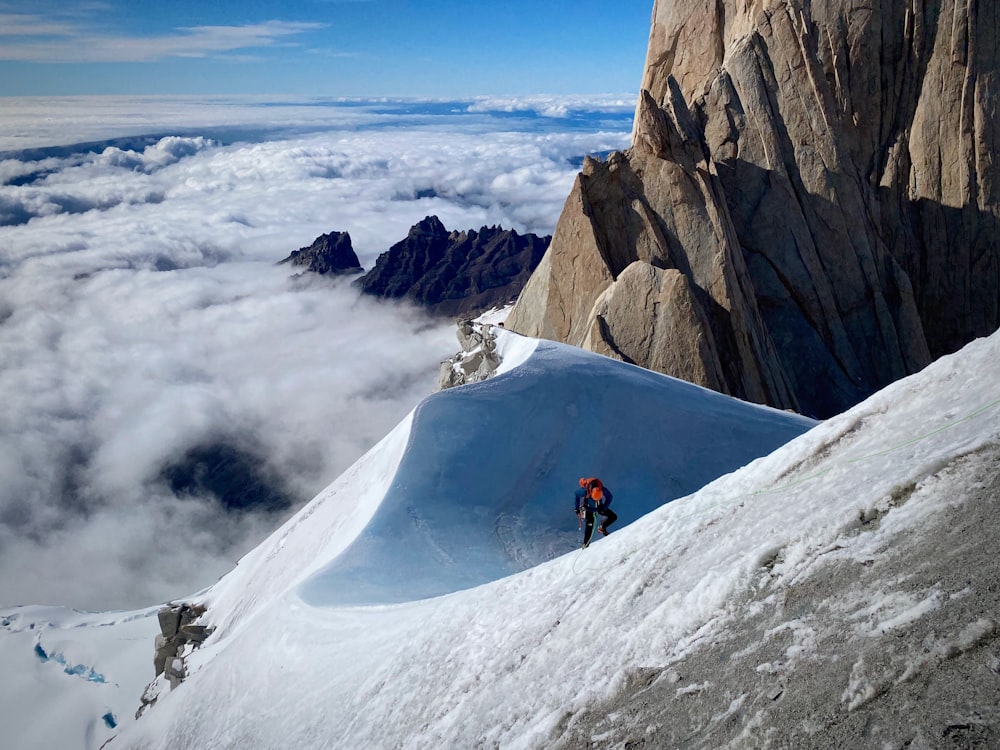 雪に覆われた山の側面を登る男
