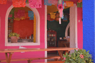a pink and blue building with a wooden bench in front of it