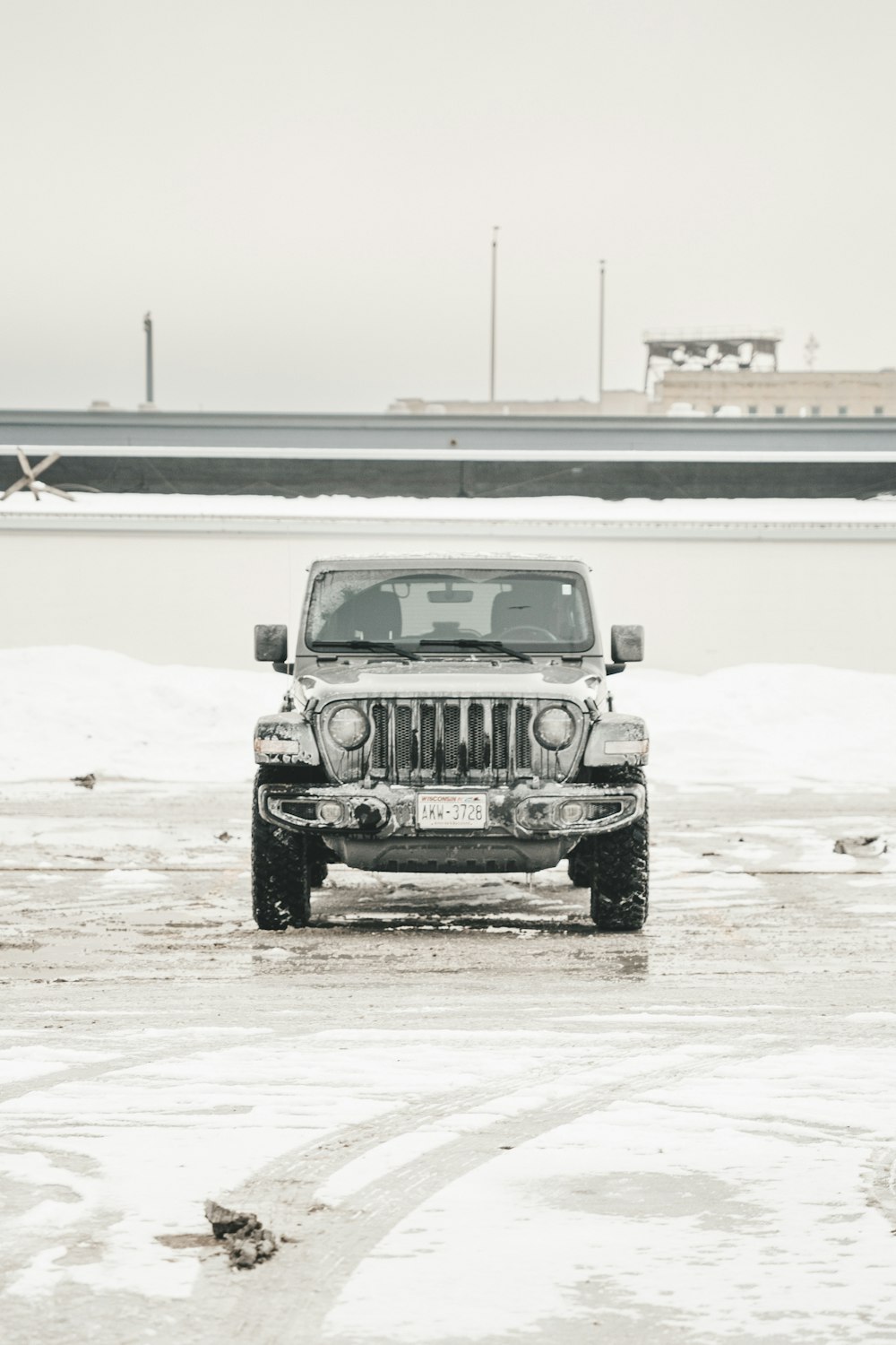 a jeep is parked in the snow by the water