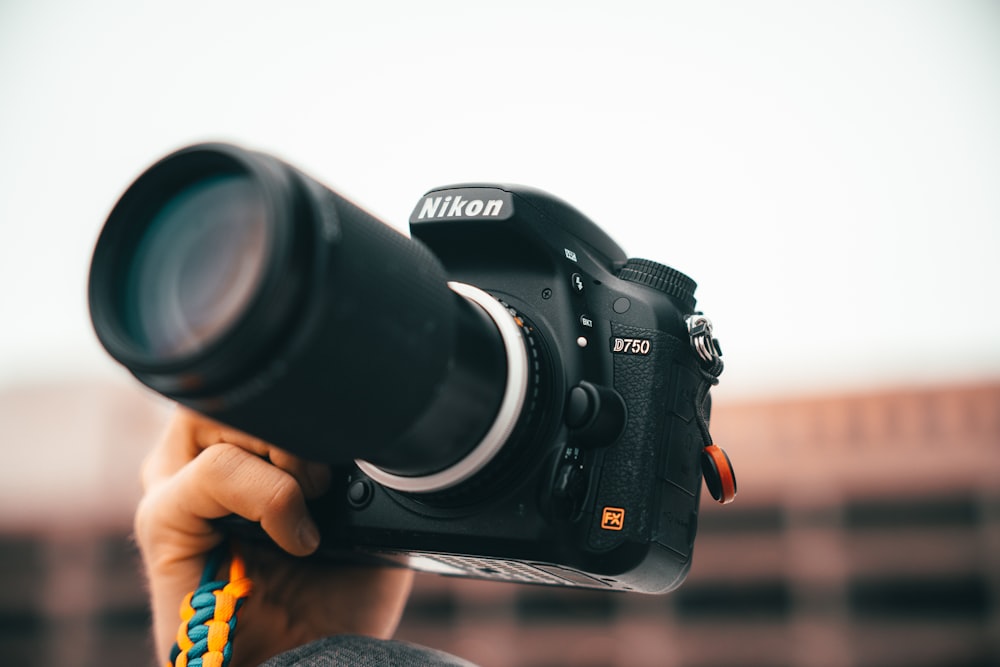 a person holding a camera with a lens attached to it