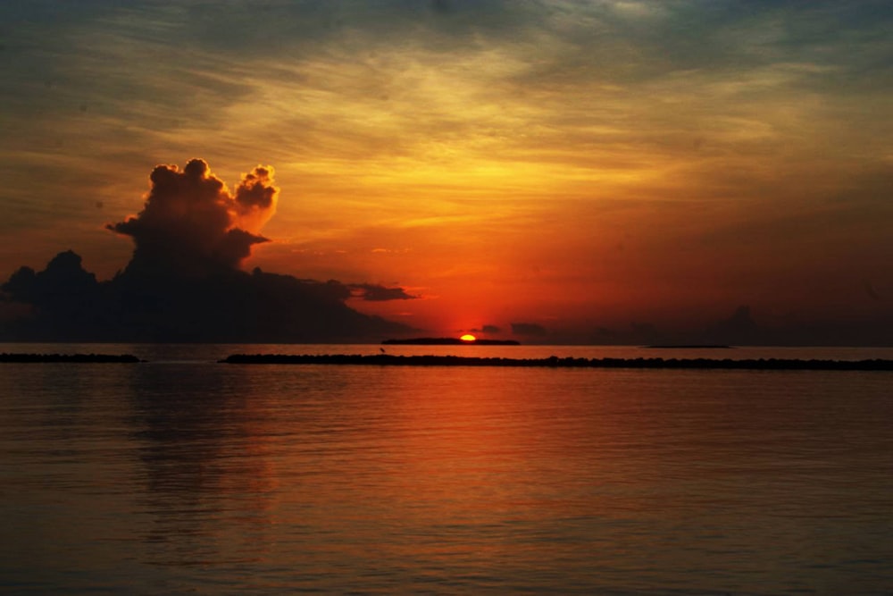 a sunset over a body of water with clouds in the sky