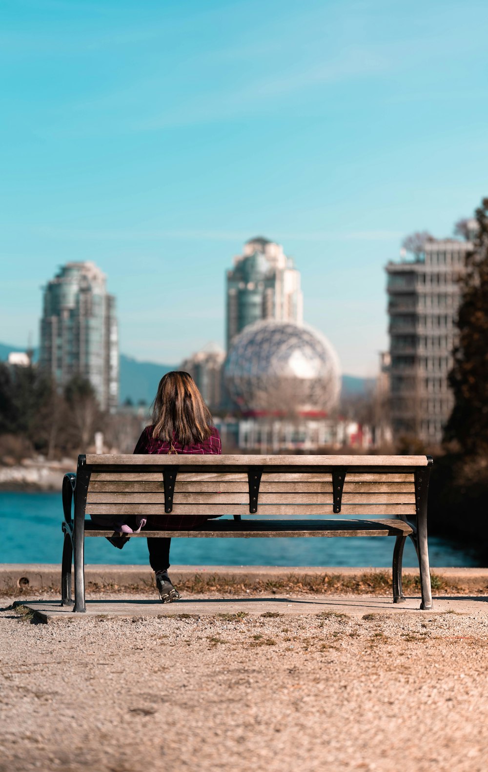 a woman sitting on a bench in front of a body of water