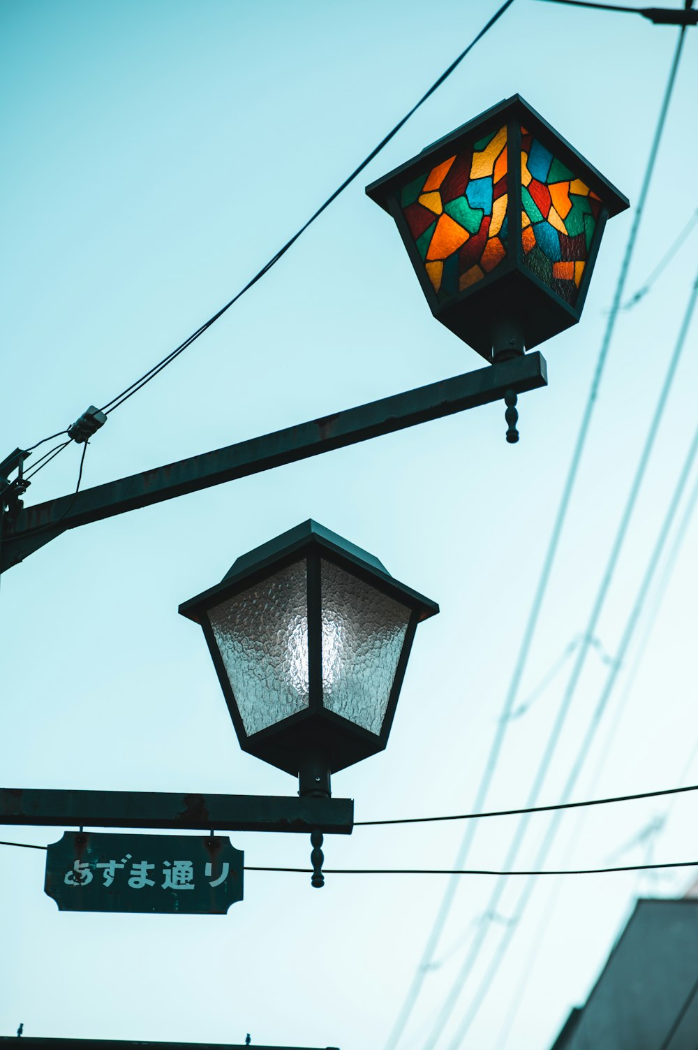 a street light with a stained glass lamp hanging off of it's side