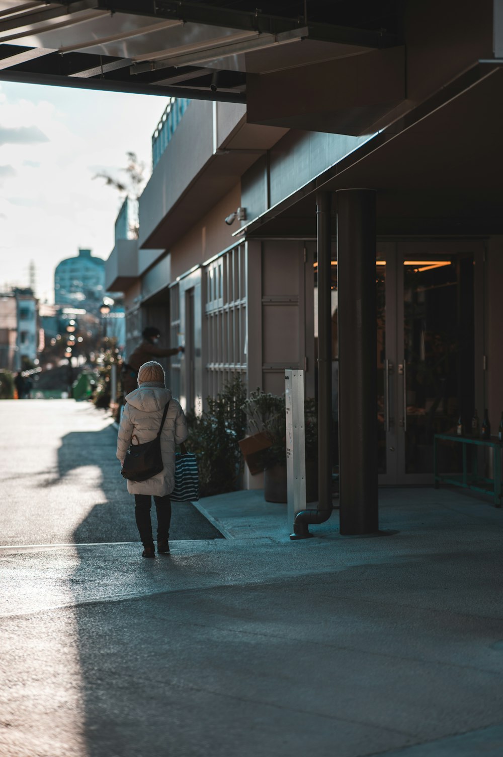 a woman walking down a sidewalk next to a building